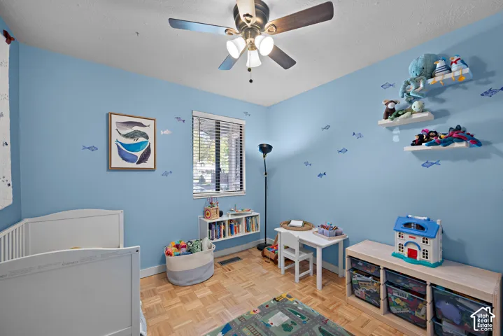 Recessed window with blinds, parquet flooring, ceiling fan with integrated lighting, and wall-mounted shelving