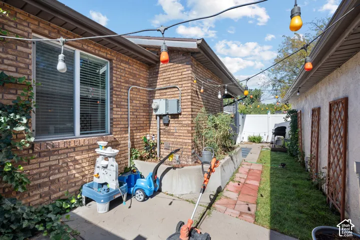 Brick exterior, white window frame, string lighting, concrete patio, grass lawn