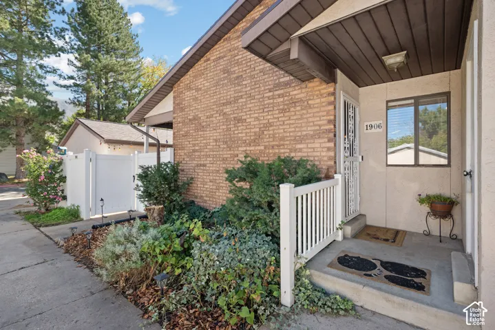Brick exterior with a covered entry, security screen door, and white picket railing