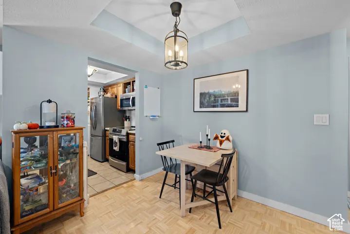 Parquet wood-finish flooring, recessed ceiling feature, and a contemporary pendant light fixture