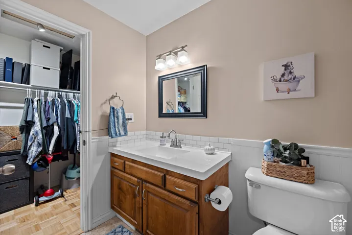 Vanity with a white countertop and base cabinetry, subway tile backsplash, framed mirror, and a wall-mounted light fixture