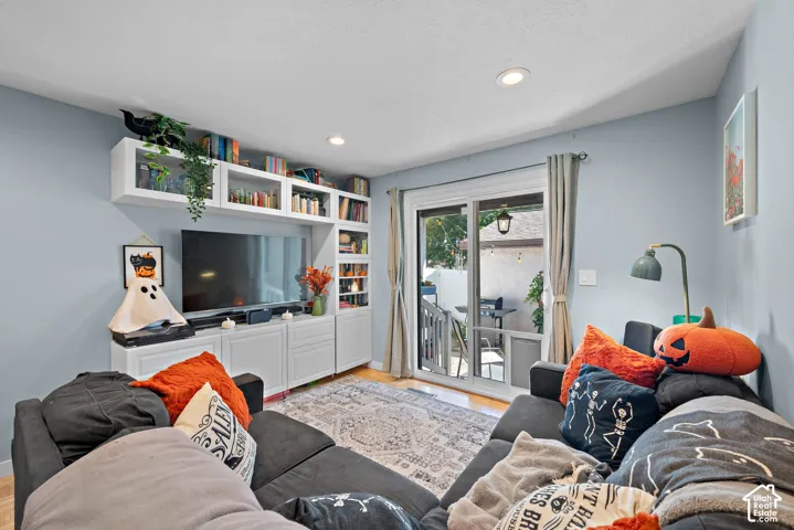 Hardwood-finish flooring, recessed ceiling lighting, built-in white cabinetry, white sliding glass door, and a built-in shelving unit
