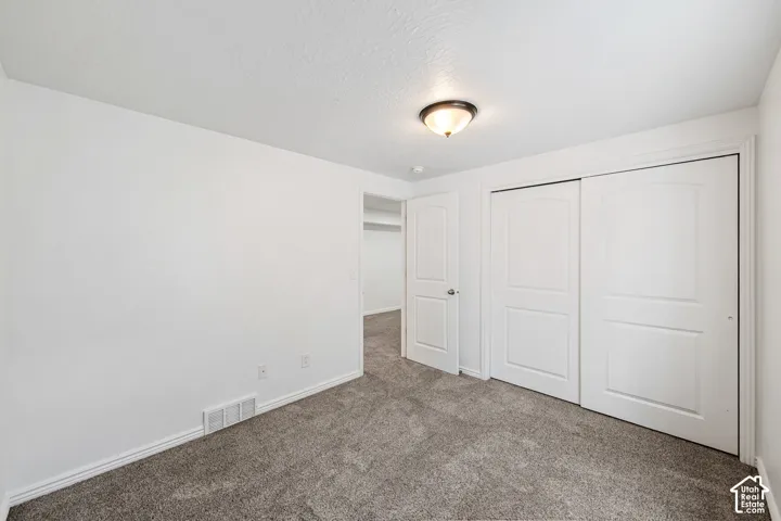Plush carpet, neutral wall finishes, flush-mount ceiling lighting, white interior doors, and sliding closet doors