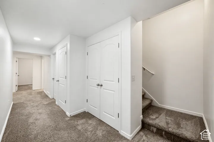 Plush carpeted flooring, multiple arched panel doors, recessed lighting, and a carpeted staircase with a white handrail