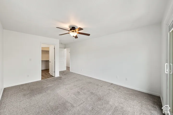 Neutral color palette, ceiling fan, sliding glass door, recessed closet with wood-finish flooring, and white interior doors