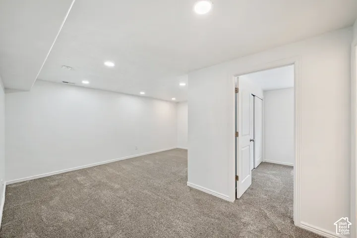 Recessed ceiling lighting, neutral carpeting, white wall finishes, and a white interior door