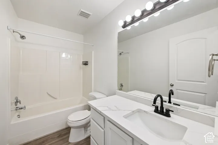 Bathroom featuring a spacious vanity with a white countertop and integrated sink, a large mirror, and a bathtub with an integrated shower