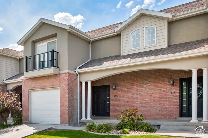 Brick and stucco exterior with an arched entryway featuring decorative columns
