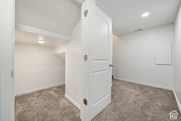 Recessed lighting, arched interior door, light gray carpeting, white painted walls, and white trim