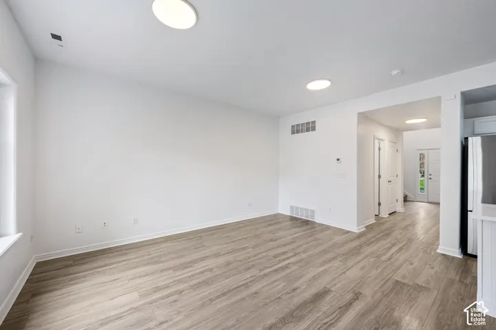 Recessed ceiling lighting, wood-finish flooring, white trim, and a white interior door