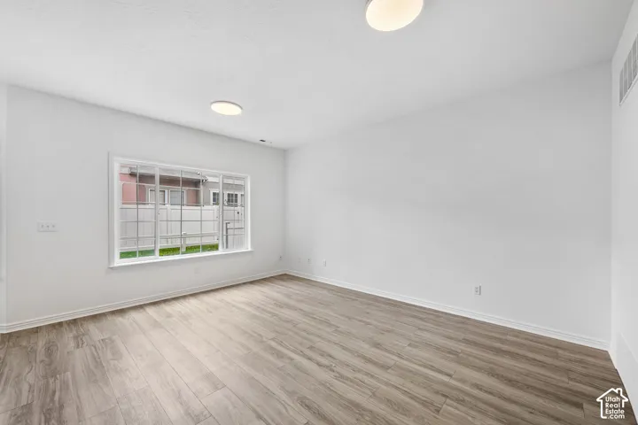 Recessed lighting fixtures, wood-finish flooring, and a large window with white trim