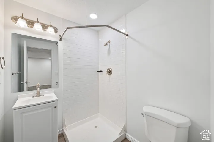 Compact bathroom featuring a single vanity with a white countertop, a rectangular mirror, and a three-light fixture