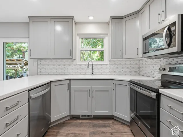Contemporary kitchen featuring light gray cabinetry, white countertops, stainless steel appliances, and a tiled backsplash