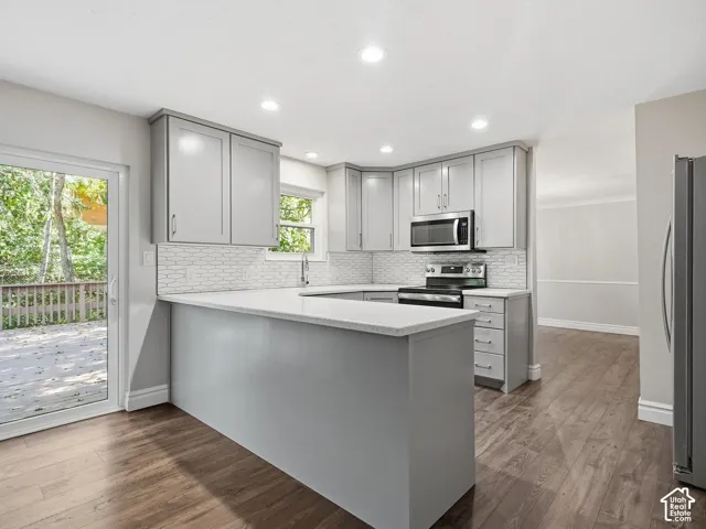 Kitchen featuring wood-finish flooring, recessed lighting, and light grey cabinetry with stainless steel appliances