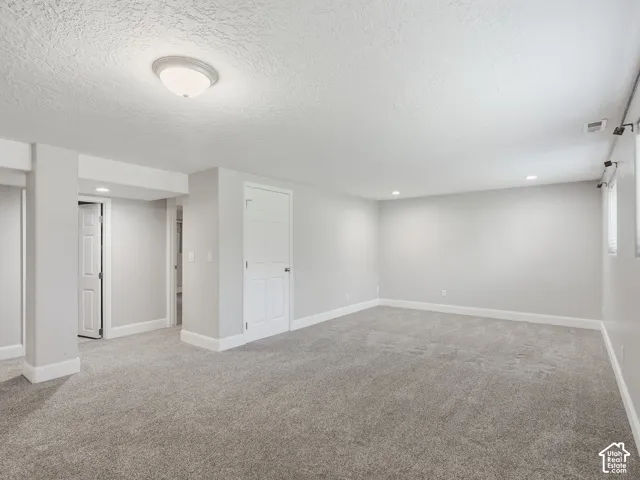 Expansive room with neutral gray walls, plush gray carpeting, and recessed lighting