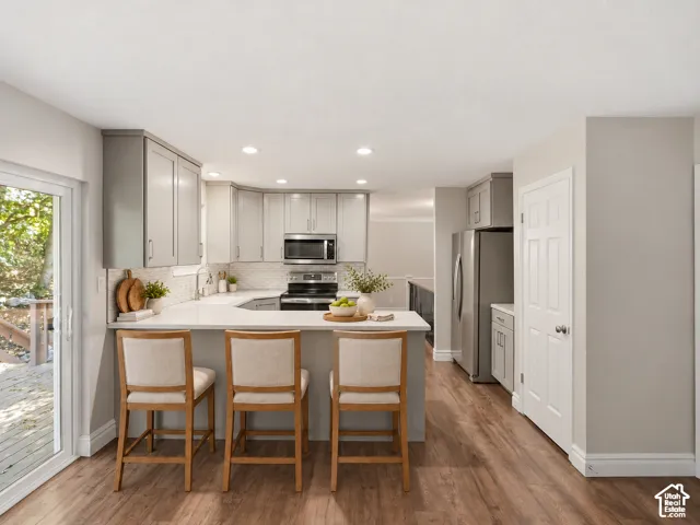 Kitchen featuring light gray cabinetry, white countertops, stainless steel appliances, and wood-finish flooring