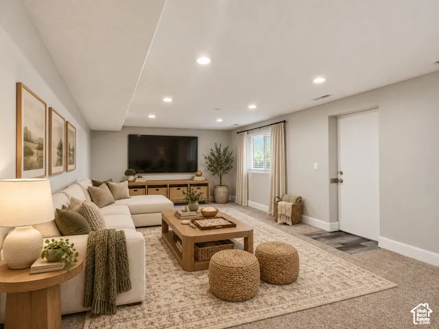 Carpeted living space featuring recessed lighting, a window with blinds and drapes, and a white door with a metal handle