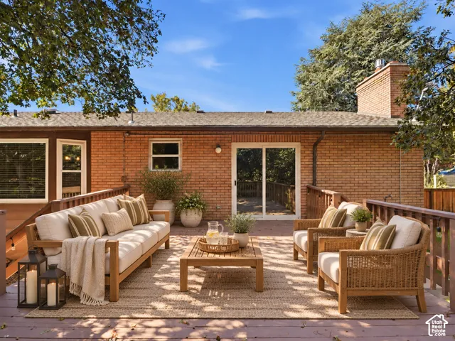 Expansive rear deck with wood railing, brick exterior, and multiple windows