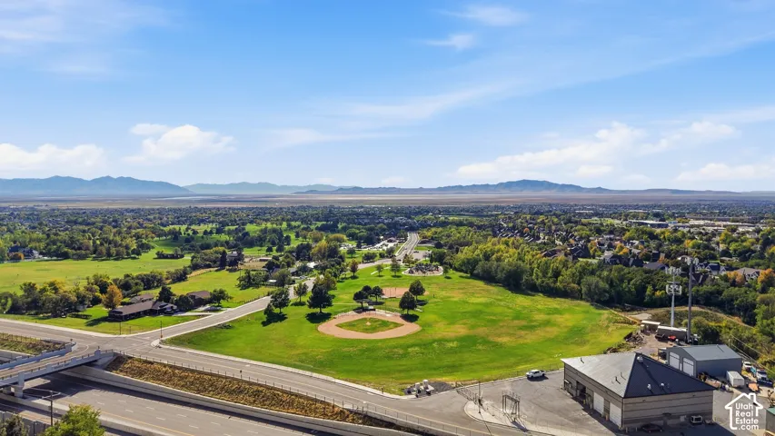 Expansive green space featuring a baseball diamond, mature trees, and mountainous background