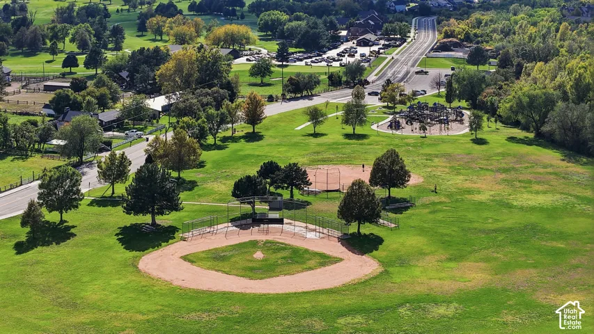 Expansive green space featuring a baseball diamond, playground, and mature trees