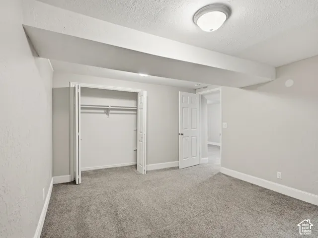 Gray carpeting, overhead lighting fixture, bifold closet doors, white interior door, and white trim