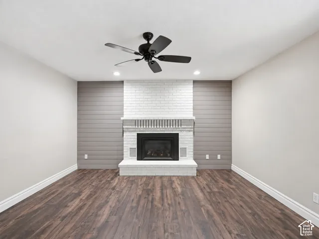 Wood-finish flooring, recessed lighting, white brick fireplace surround, black fireplace insert, and a black ceiling fan