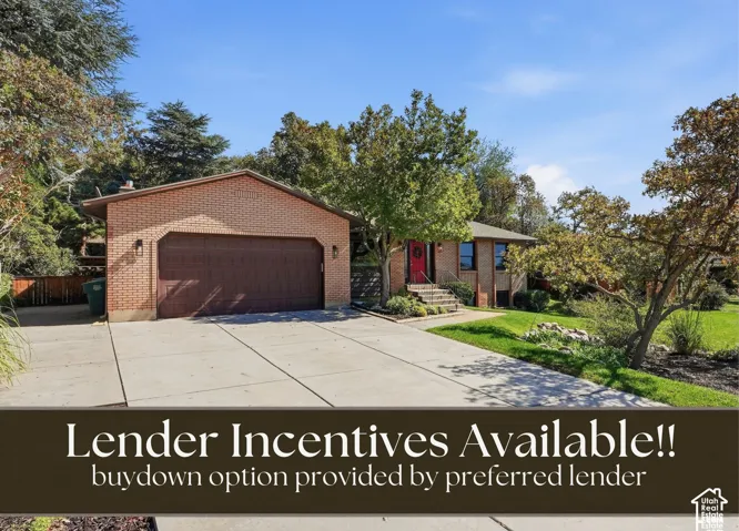 Brick exterior with attached garage, concrete driveway, and established trees