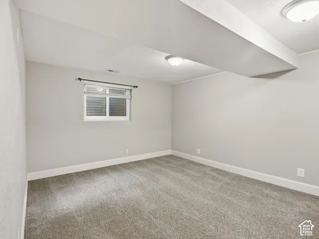 Wall-to-wall carpeting with light gray walls, recessed window with blinds, and two flush-mount ceiling lights