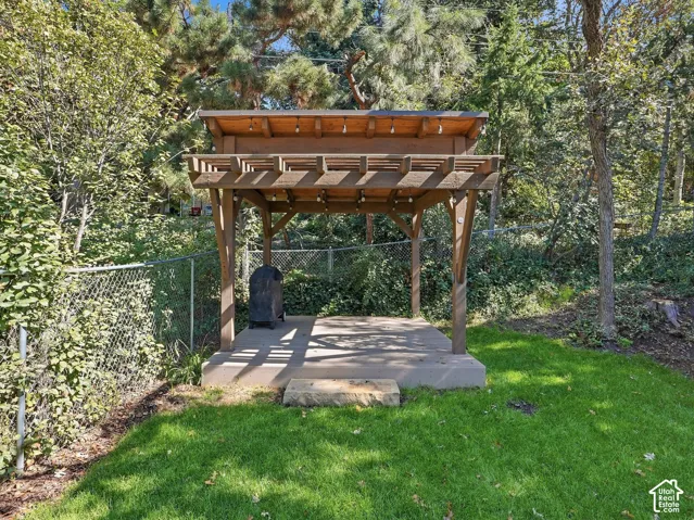 Outdoor pergola with a solid roof, concrete pad, and surrounding natural landscaping