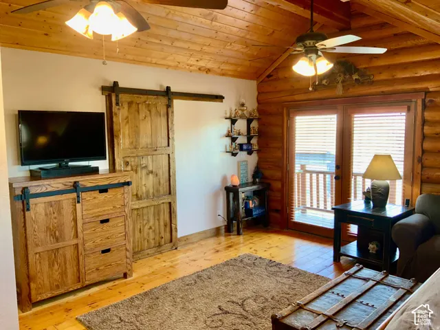 Vaulted wood-finish ceiling, wood-finish flooring, log wall construction, wood-finish French doors, and a wood-finish barn door