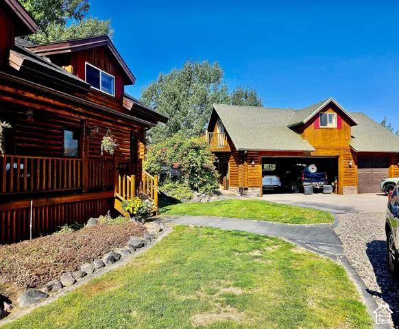 Log-style exterior construction with a covered porch, attached garage, and a gravel driveway