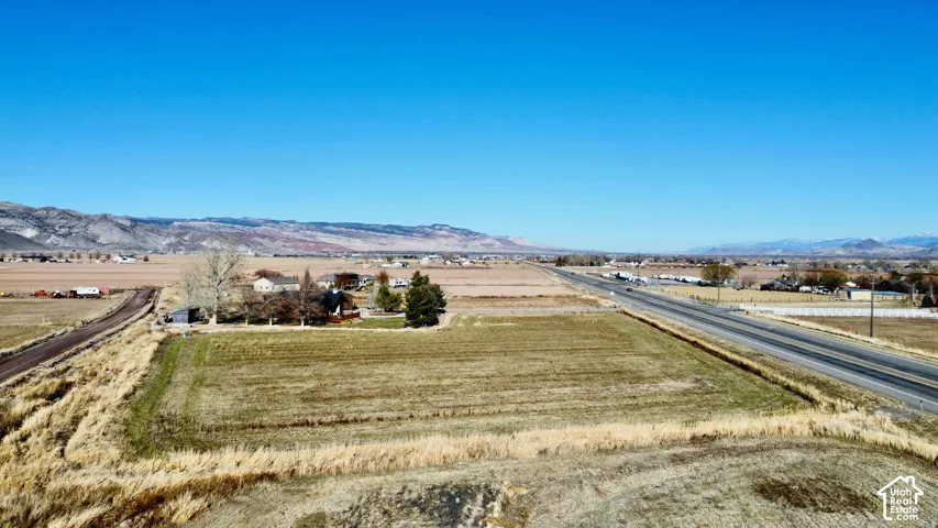 Expansive open land featuring a paved road, dirt road, and distant mountain ranges