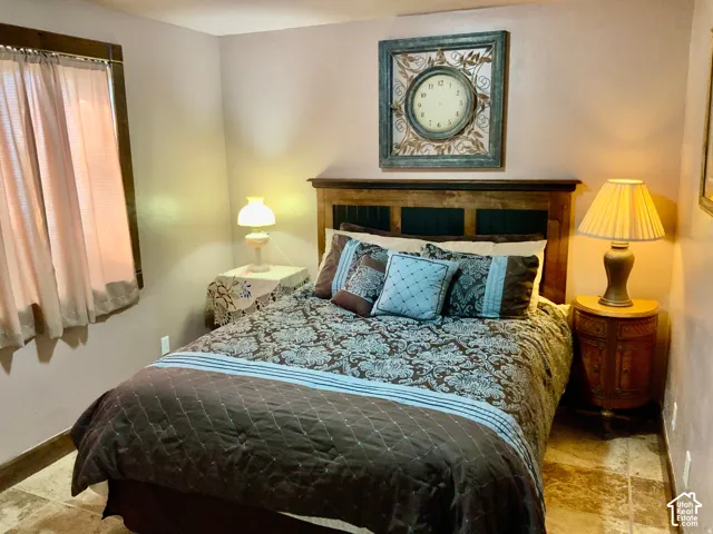 Wood-finish headboard with panel detailing, tiled flooring, window with wood-frame trim