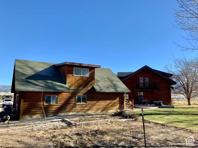 Log cabin style exterior, multi-level structure, green asphalt shingle roof, upper-level balcony, ground-level patio