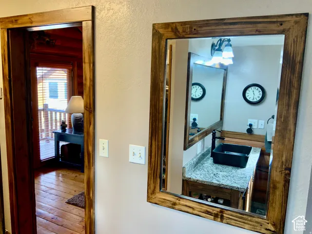 Wood-framed mirror over a vanity with a light-toned countertop and black vessel sink