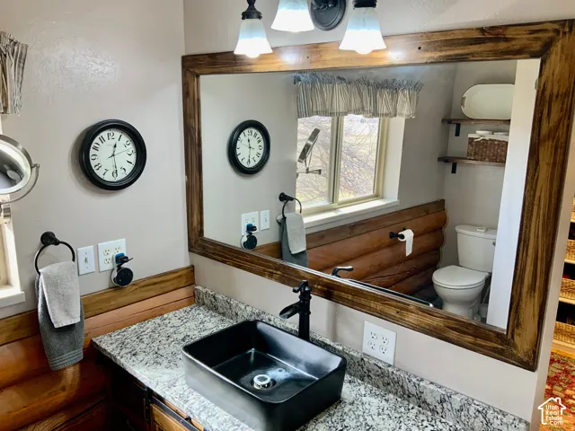 Bathroom featuring a wood-framed mirror, vessel sink, granite countertop, and wood-finish cabinetry