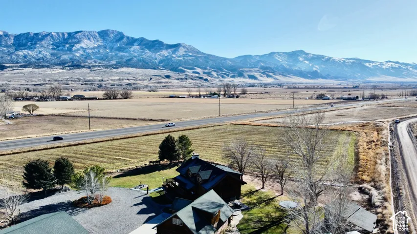 Mountain backdrop with snow-capped peaks, expansive landscape, and a dark-toned residential structure