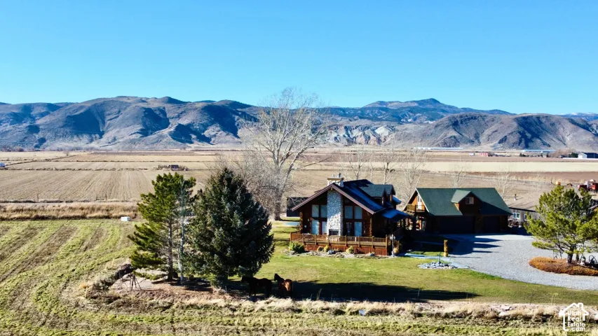 Expansive property featuring a gravel driveway, landscaped grounds with mature trees, and a two-story residence with a stone and wood exterior