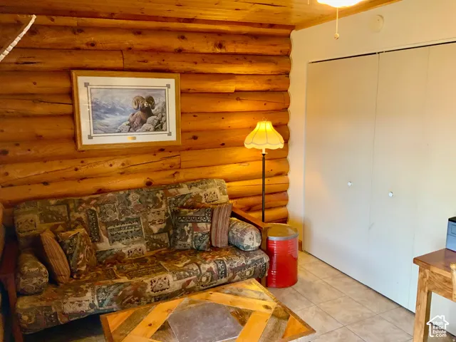 Log wall construction, tile flooring, built-in bi-fold closet, and wood ceiling paneling
