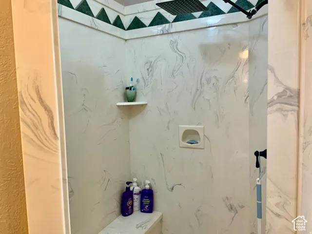 Shower stall featuring a built-in bench, corner shelf, and a wall-mounted soap dish