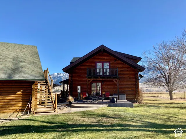Log cabin exterior with a second-story balcony featuring a dark wood railing