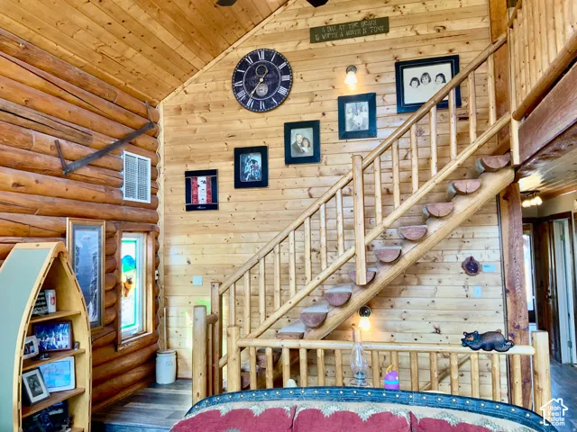 Log cabin interior featuring exposed log walls, natural wood paneling, and a wood staircase with open risers
