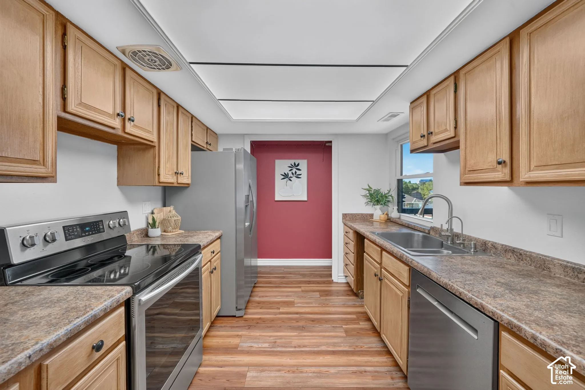 Galley kitchen with stainless steel appliances, plenty of cabinets, and a double sink under the window.