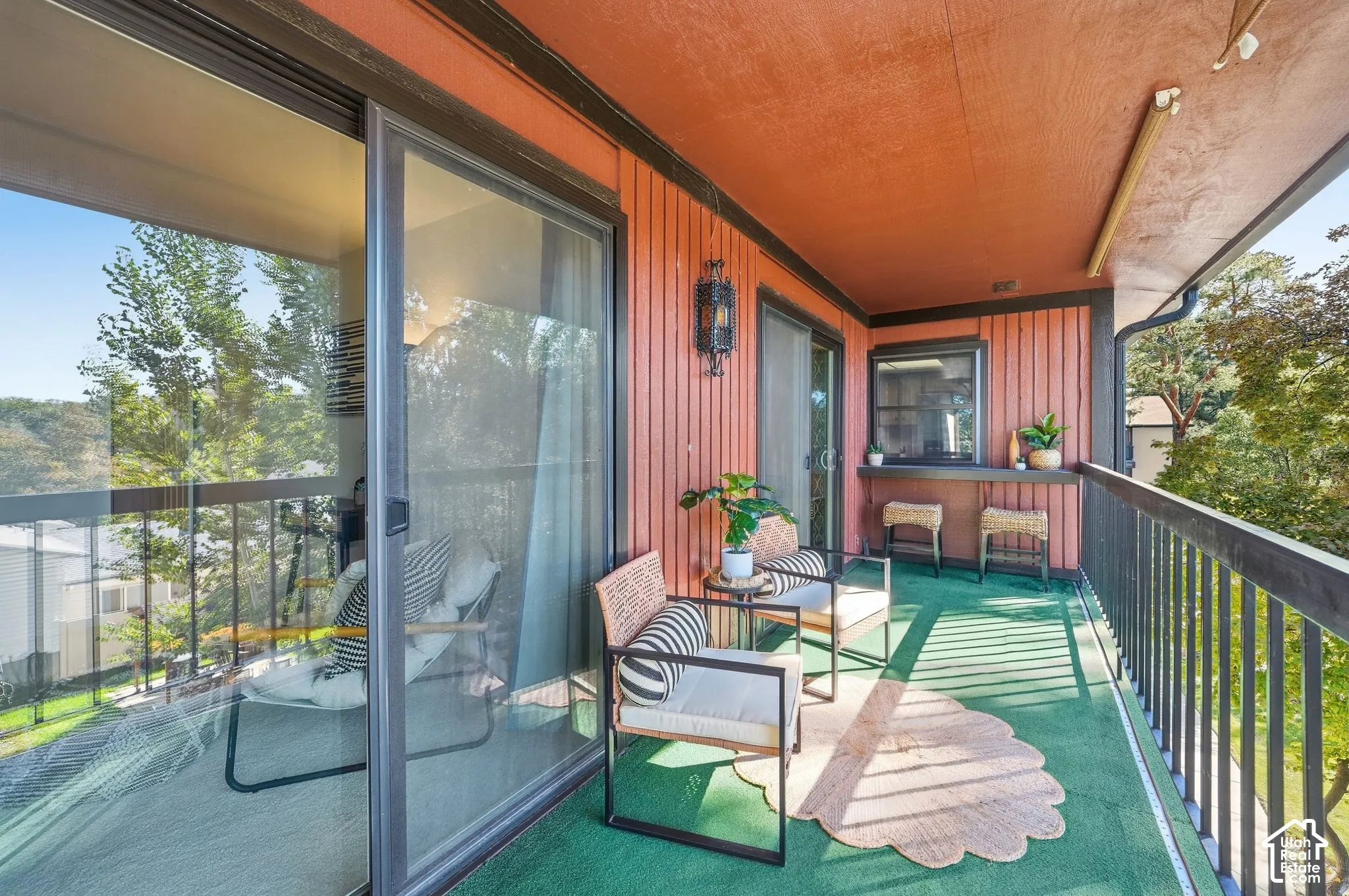 Expansive covered deck with floor-to-ceiling sliding glass doors, copper ceiling, and metal railings overlooking mature landscaping
