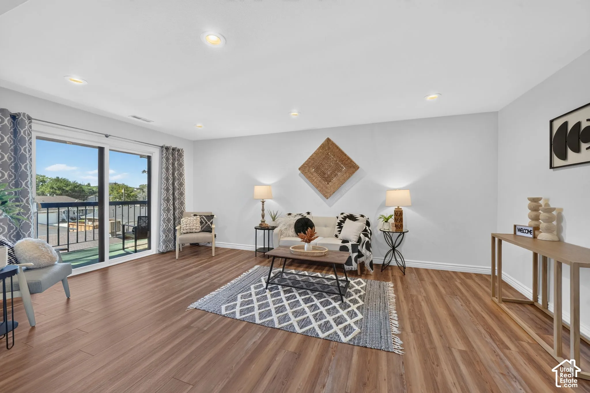 Wood-finish flooring, recessed lighting, and a sliding glass door to a balcony with black metal railings