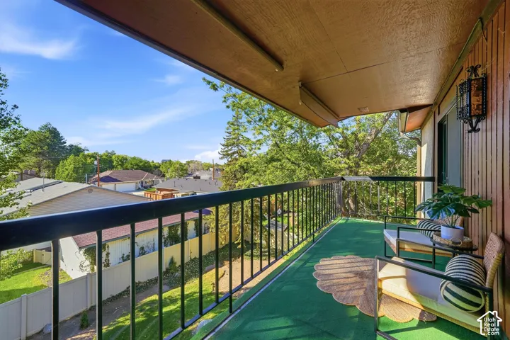 Balcony featuring green turf flooring, black metal railing, and a decorative wall sconce
