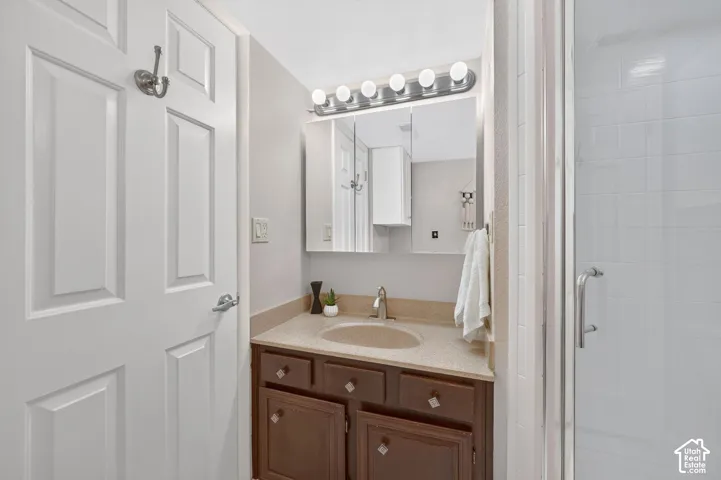 The ensuite has a wood vanity, a lighted mirror, and a shower.