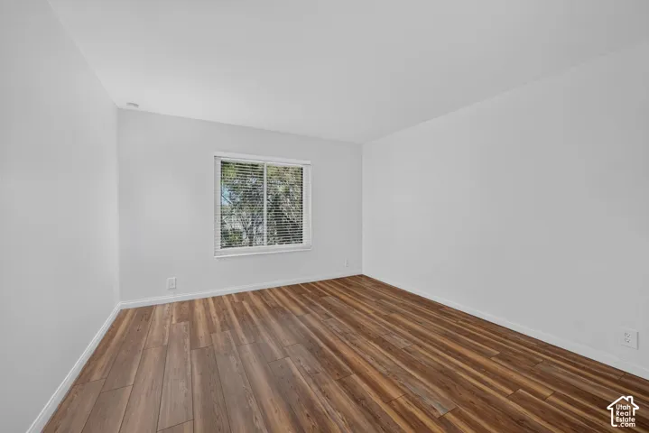 The second bedroom has laminate flooring and a window that looks out onto greenery.