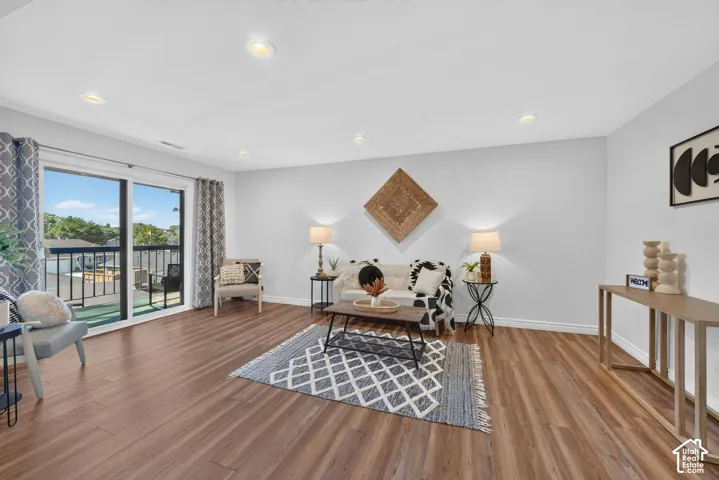 Wood-finish flooring, recessed lighting, and a sliding glass door to a balcony with black metal railings