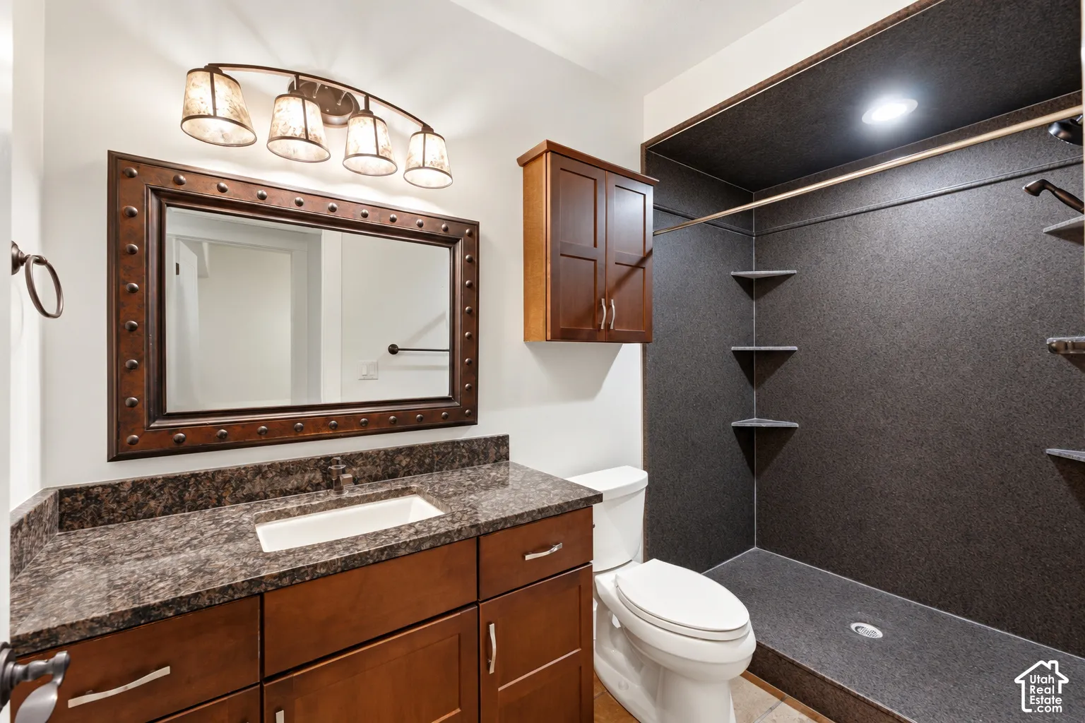 Wood-finish vanity with an integrated rectangular sink, stone countertop, and decorative framed mirror